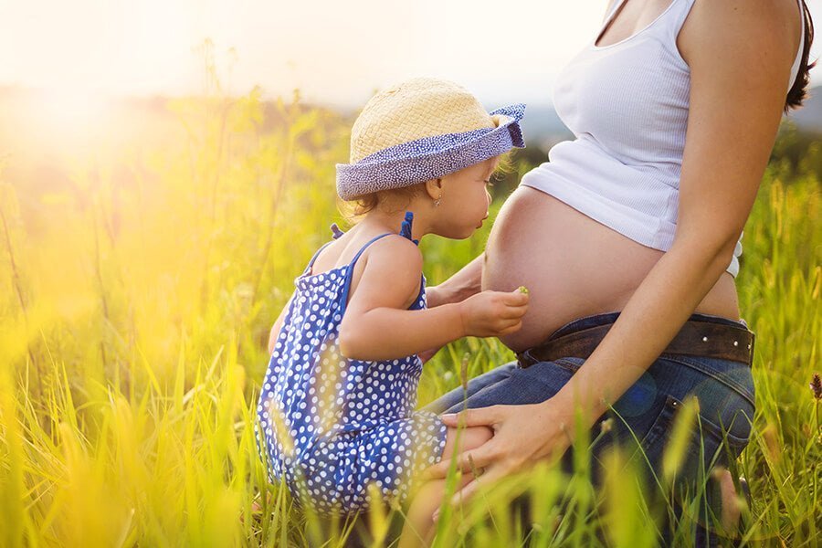 Toddler kissing pregnant mums stomoach Benefits of Ghee for Postpartum Mums - OMGhee