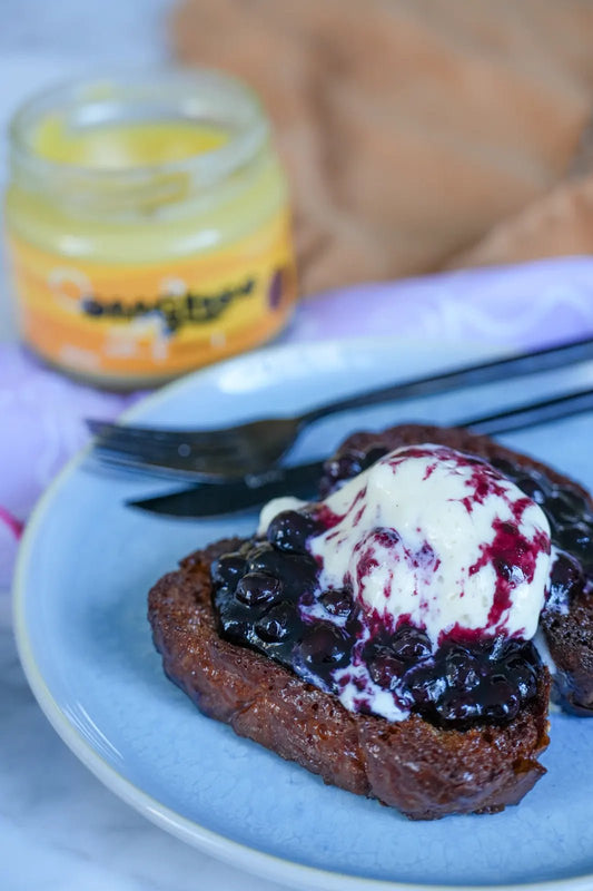 Ghee, Honey & Cinnamon Brioche lathered with cream with a jar of OMGhee ghee in the background.