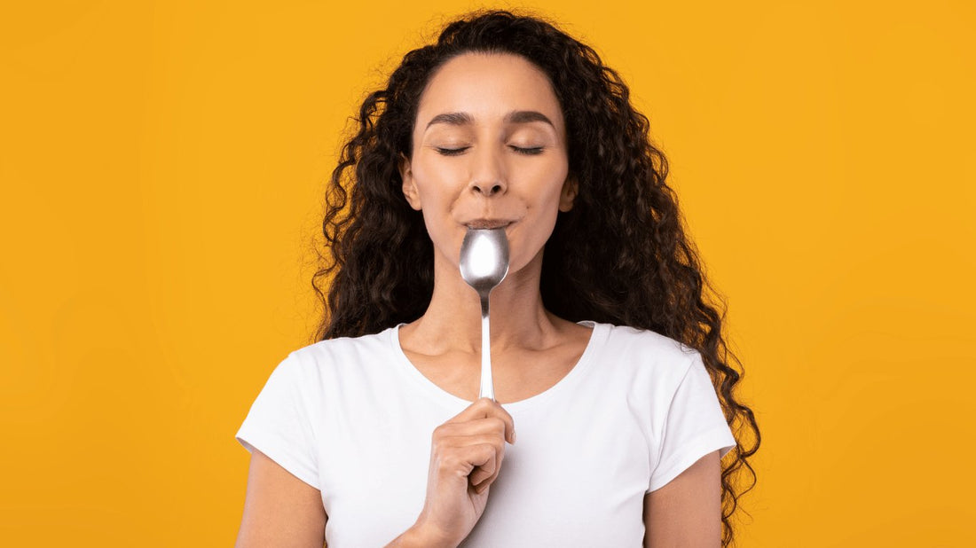 Lady with curly hair liking smppon with yellow background What Does Ghee Taste Like? - OMGhee
